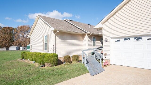 view of home's exterior featuring concrete driveway, roof with shingles, and a yard