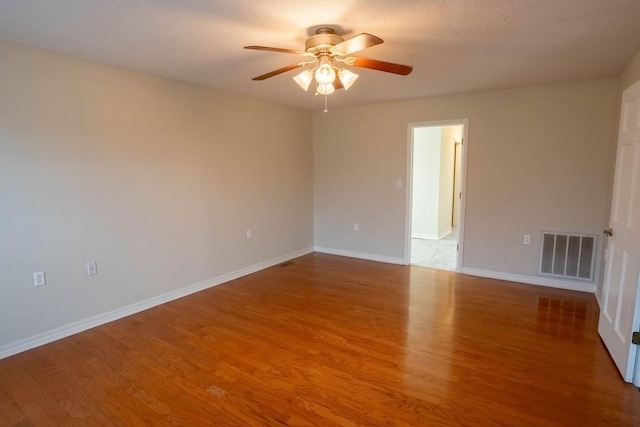 unfurnished room featuring a ceiling fan, baseboards, visible vents, and wood finished floors