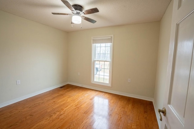 spare room with light wood finished floors, visible vents, baseboards, ceiling fan, and a textured ceiling