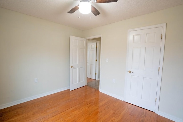 unfurnished bedroom featuring baseboards, ceiling fan, a textured ceiling, and light wood finished floors