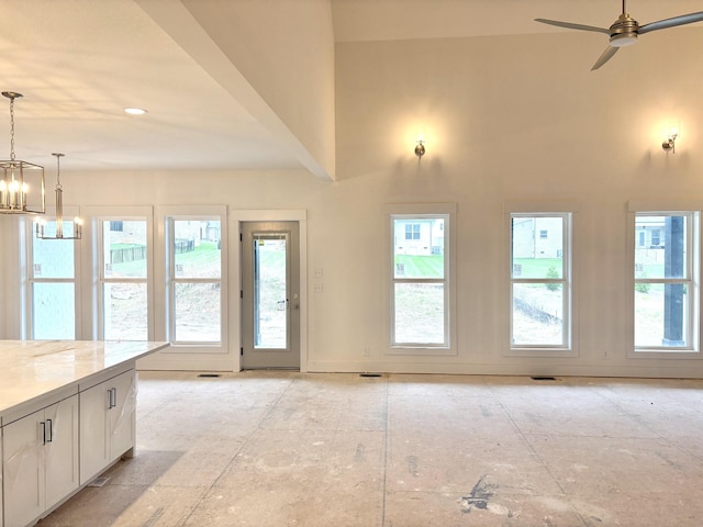 entryway featuring ceiling fan with notable chandelier, visible vents, a towering ceiling, and a wealth of natural light