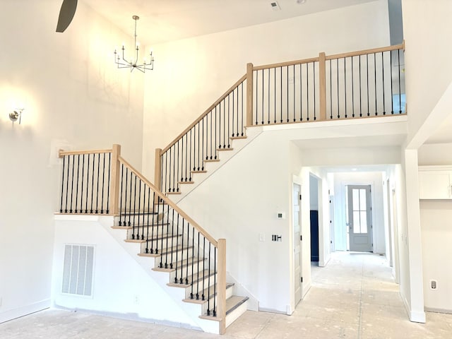 stairway featuring baseboards, visible vents, a notable chandelier, and a high ceiling