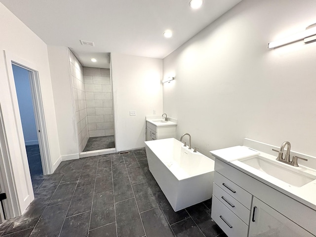 full bathroom with a freestanding bath, visible vents, two vanities, and a sink