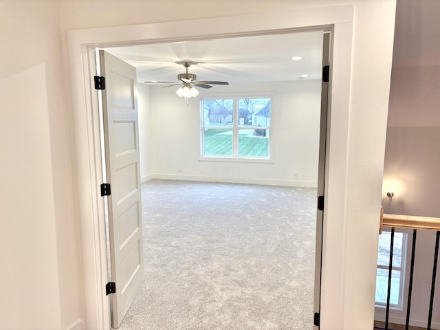 empty room with ceiling fan, baseboards, and light colored carpet