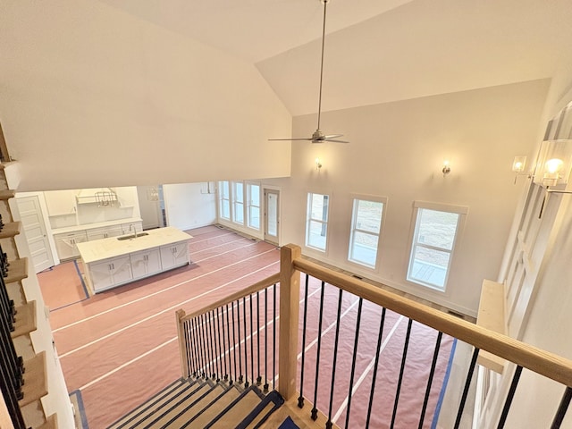 stairs featuring high vaulted ceiling and a ceiling fan