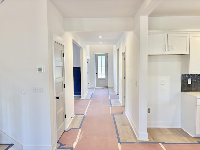 hall with light wood-type flooring, baseboards, and recessed lighting