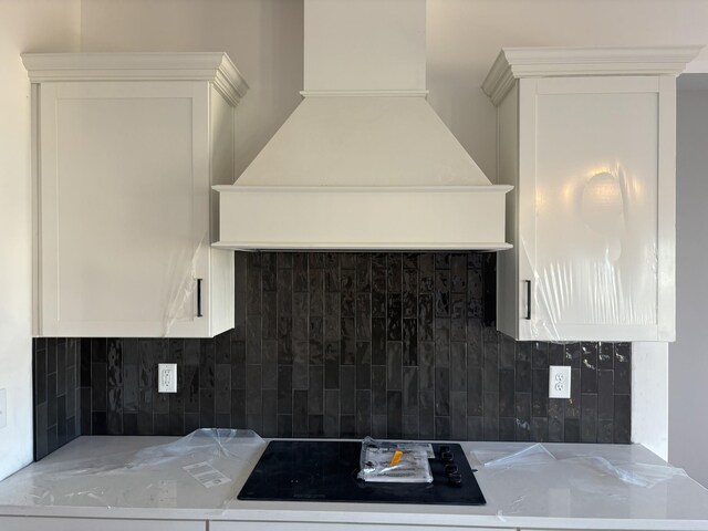 kitchen featuring light countertops, custom range hood, decorative backsplash, and white cabinetry