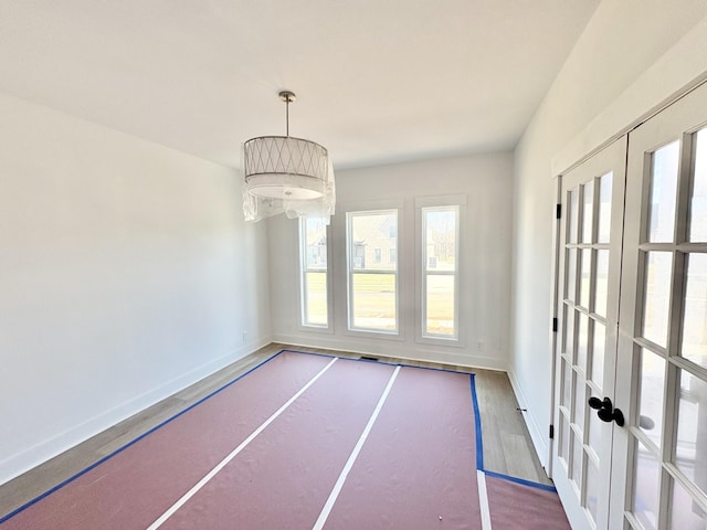 unfurnished dining area with plenty of natural light, baseboards, and french doors