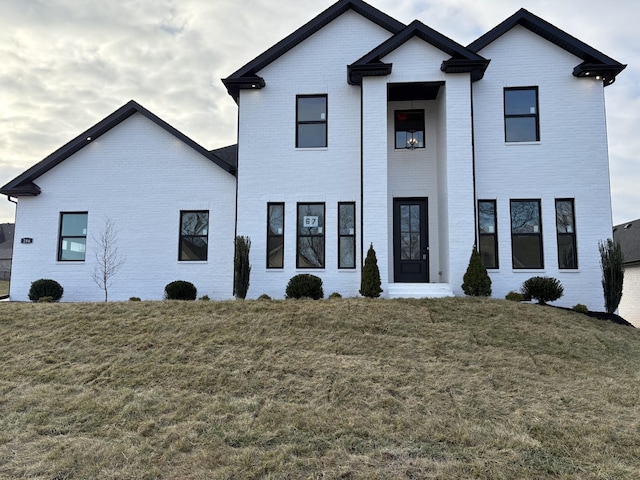 modern farmhouse with a front yard and brick siding