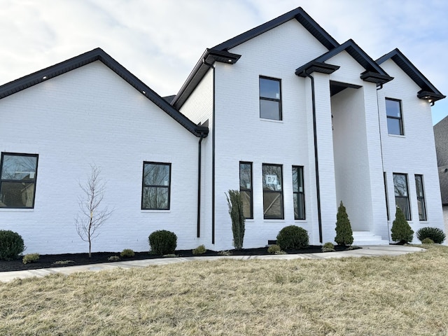 modern inspired farmhouse featuring a front yard and brick siding