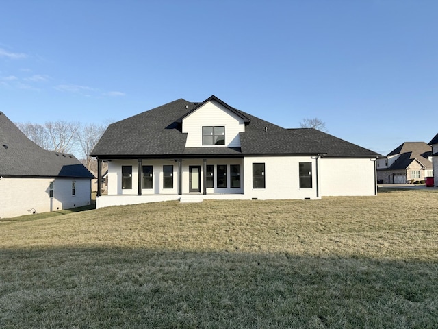 back of property featuring a shingled roof and a lawn