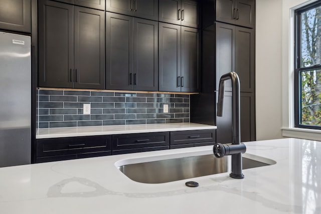 kitchen featuring stainless steel fridge, light stone counters, a healthy amount of sunlight, and tasteful backsplash