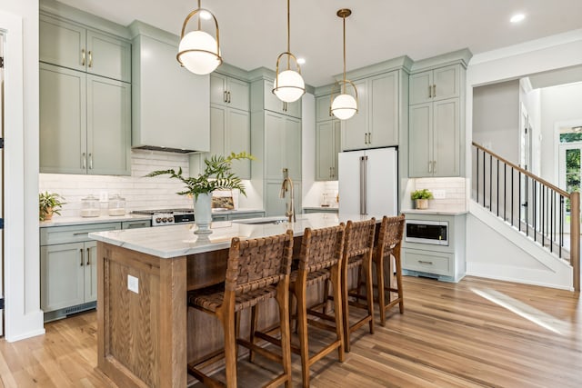 kitchen featuring a kitchen breakfast bar, light stone countertops, an island with sink, light hardwood / wood-style floors, and custom range hood