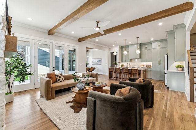 living room featuring ceiling fan, french doors, beamed ceiling, and light wood-type flooring