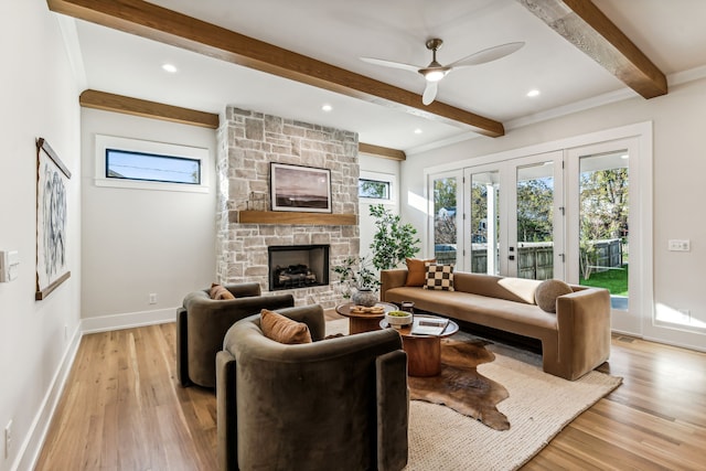 living room featuring ceiling fan, crown molding, beam ceiling, light hardwood / wood-style flooring, and a fireplace