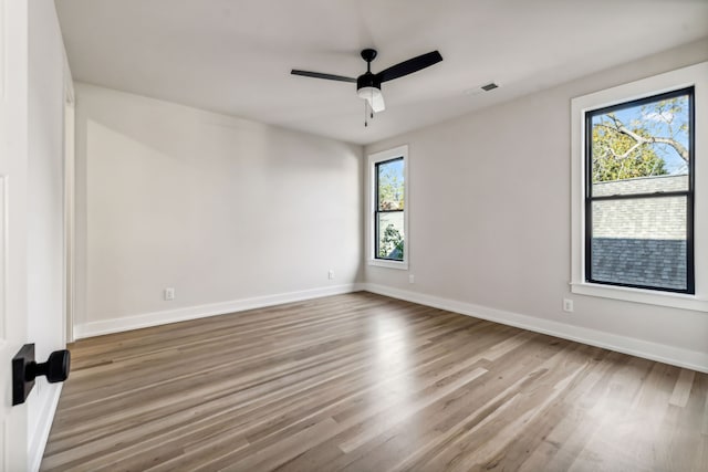 empty room with ceiling fan, a healthy amount of sunlight, and wood-type flooring