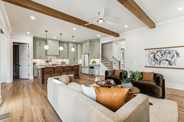 living room with beam ceiling, light hardwood / wood-style flooring, ceiling fan, and crown molding