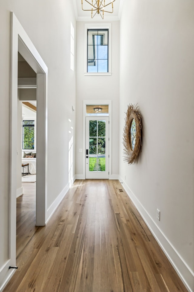 foyer featuring light wood-type flooring, an inviting chandelier, and ornamental molding