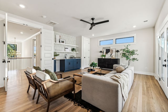 living room with plenty of natural light, ceiling fan with notable chandelier, and light hardwood / wood-style flooring