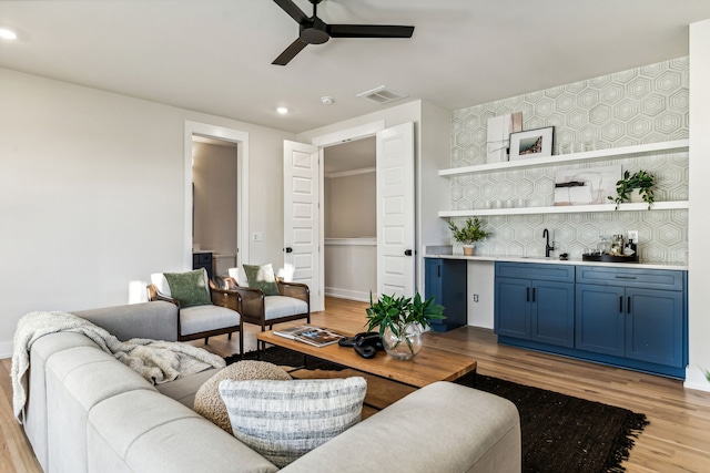 living room featuring ceiling fan, light wood-type flooring, and sink