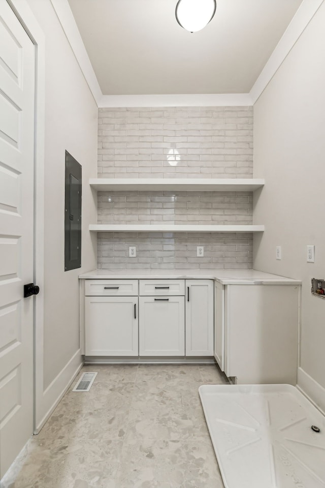 kitchen with white cabinetry, backsplash, and electric panel