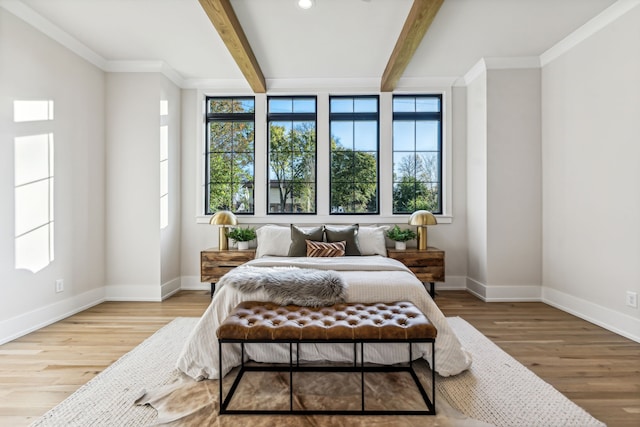 bedroom featuring beamed ceiling, wood-type flooring, and multiple windows