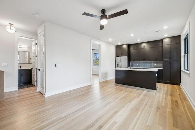 kitchen featuring a center island, stainless steel refrigerator with ice dispenser, ceiling fan, decorative backsplash, and light wood-type flooring