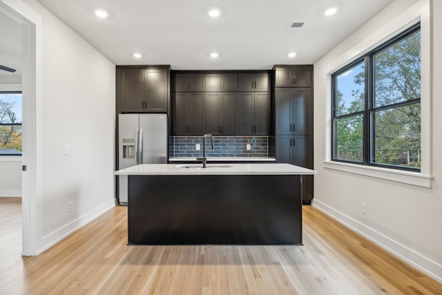 kitchen with sink, a wealth of natural light, and an island with sink