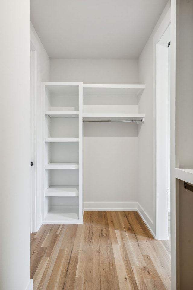 walk in closet with light hardwood / wood-style floors