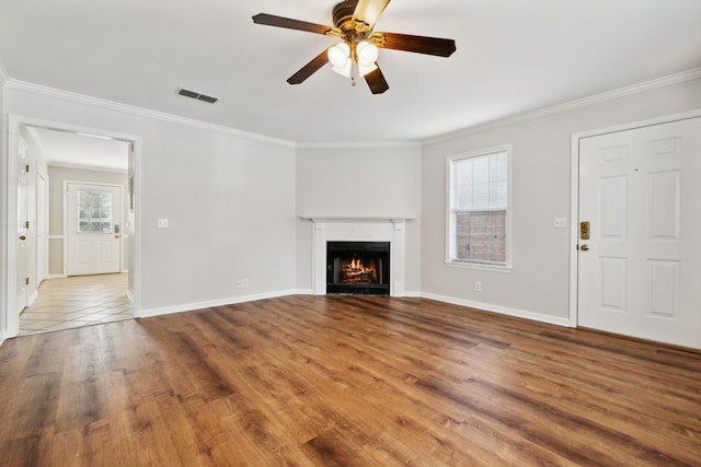 unfurnished living room featuring wood-type flooring, crown molding, and a healthy amount of sunlight