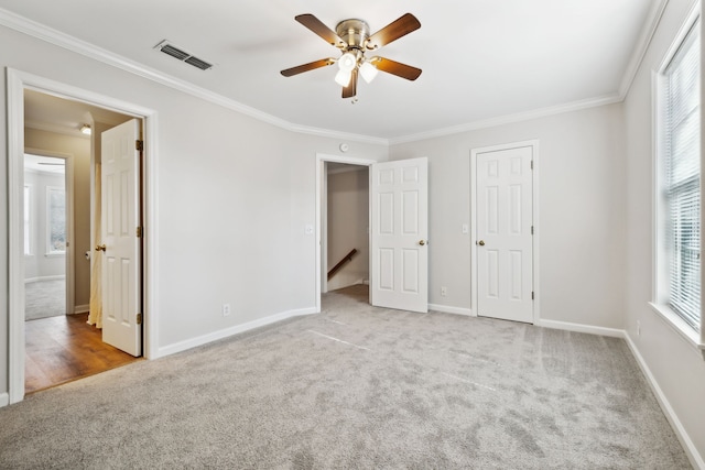 unfurnished bedroom with multiple windows, ceiling fan, light carpet, and ornamental molding