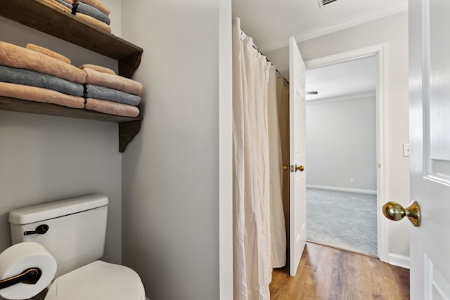 bathroom featuring hardwood / wood-style flooring, toilet, and ornamental molding