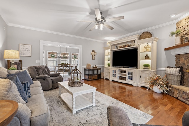 living room with ceiling fan, hardwood / wood-style floors, crown molding, and a stone fireplace