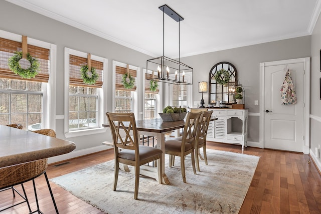 dining area featuring crown molding, light hardwood / wood-style floors, and a chandelier