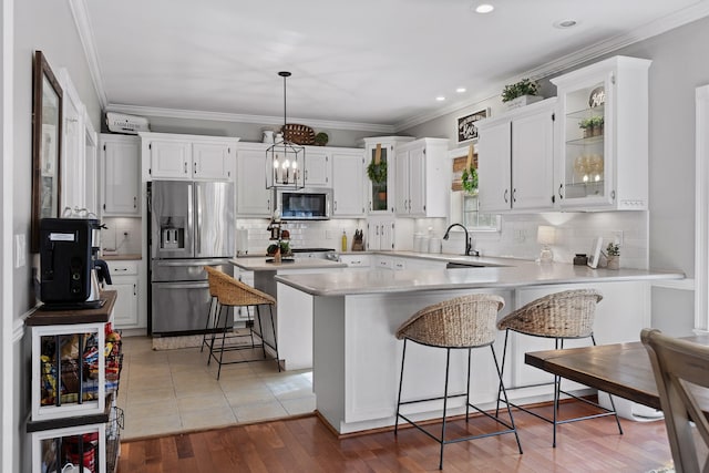 kitchen with white cabinetry, a kitchen bar, hanging light fixtures, and stainless steel appliances