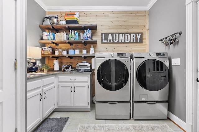 washroom with crown molding, washer and dryer, light tile patterned flooring, cabinets, and wood walls