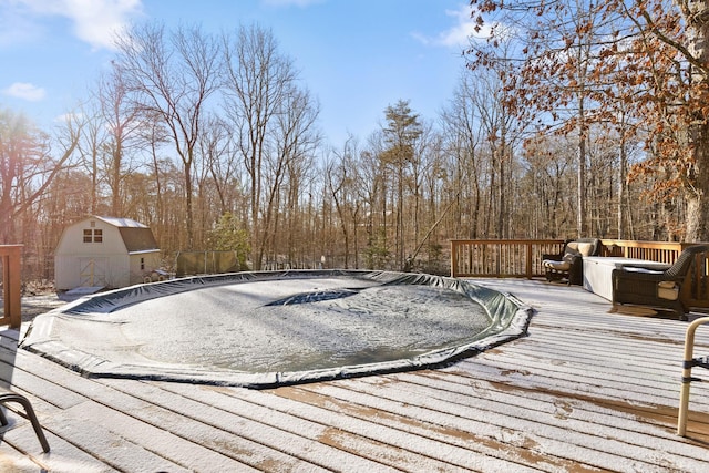 view of swimming pool with a storage shed and a deck