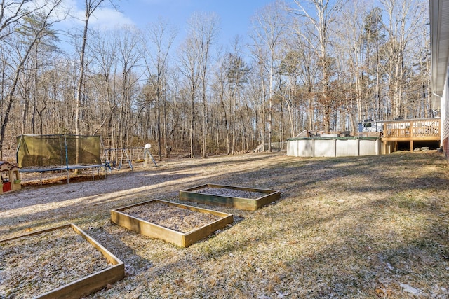 view of yard featuring a covered pool, a playground, and a trampoline