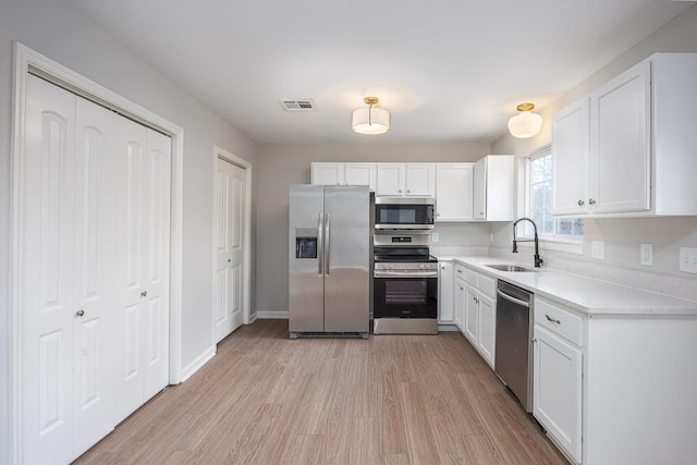 kitchen featuring white cabinets, light wood-type flooring, stainless steel appliances, and sink