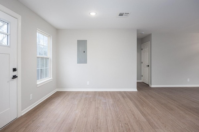 spare room with electric panel and light hardwood / wood-style flooring