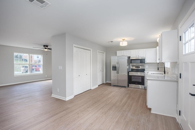 kitchen with ceiling fan, sink, light hardwood / wood-style floors, white cabinets, and appliances with stainless steel finishes