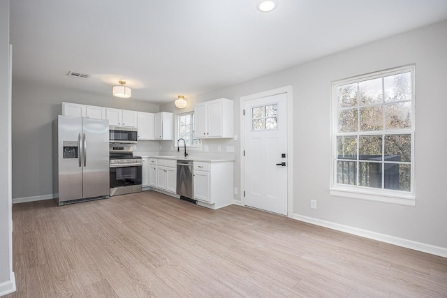 kitchen featuring light wood-type flooring, white cabinetry, and appliances with stainless steel finishes