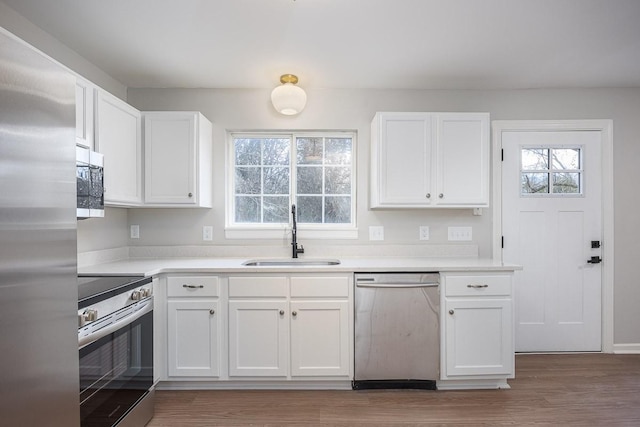 kitchen with hardwood / wood-style floors, white cabinetry, sink, and appliances with stainless steel finishes