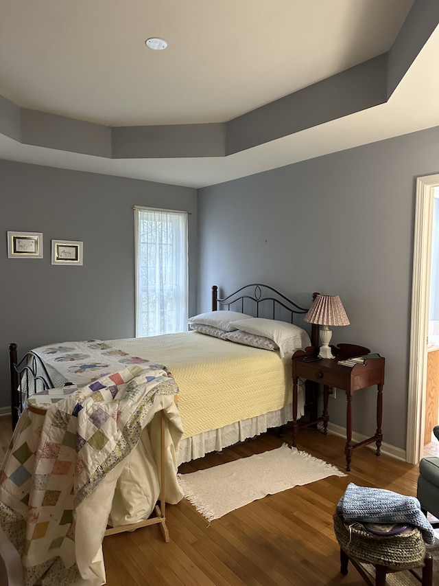 bedroom featuring hardwood / wood-style flooring and a raised ceiling