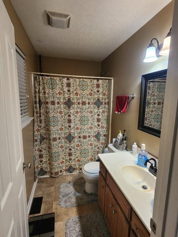 bathroom with tile patterned flooring, vanity, a textured ceiling, and toilet