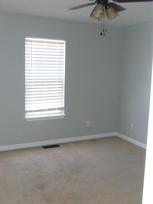 unfurnished room with ceiling fan, light colored carpet, and plenty of natural light