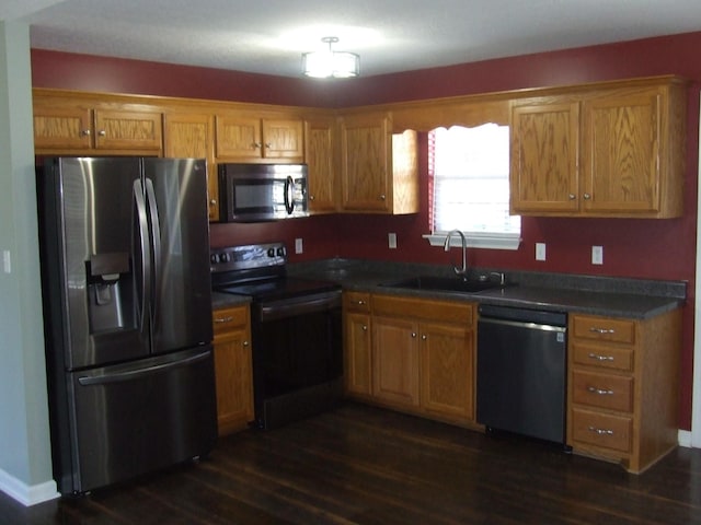 kitchen with appliances with stainless steel finishes, sink, and dark wood-type flooring