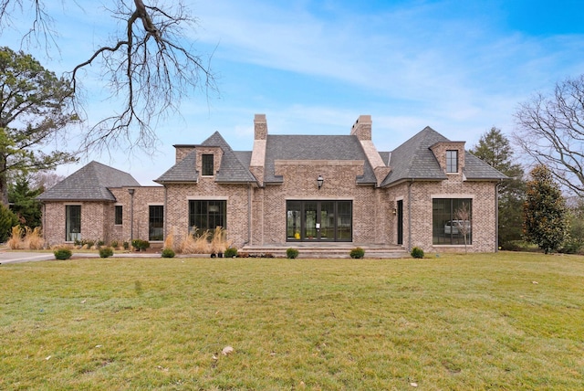 view of front of home with a front yard, brick siding, and a chimney