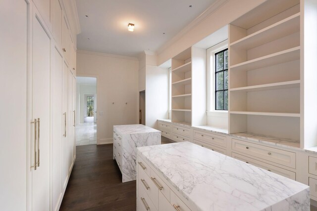 interior space with dark wood finished floors, open shelves, white cabinetry, crown molding, and a center island