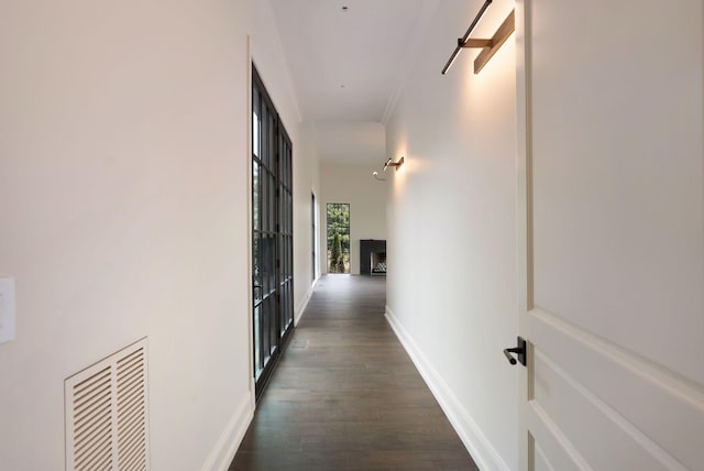 hall featuring dark wood-style floors, visible vents, and baseboards